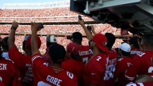 Fans take pictures of opening kickoff from southwest concourse.