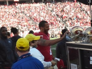 Colin Kaepernick exchanges his radio helmet for his flat-brimmed hat after throwing a TD pass