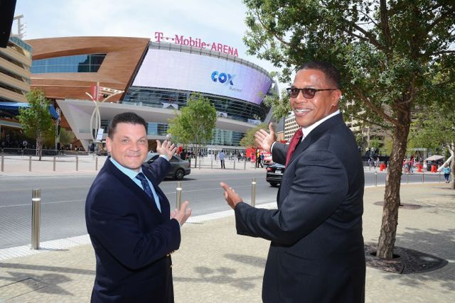 Jeff Breaux, vice president of western operations, Cox Business, (left) and Derrick R. Hill, vice president, Cox Business/Hospitality Network, gesture toward the exterior digital signage at T-Mobile Arena.